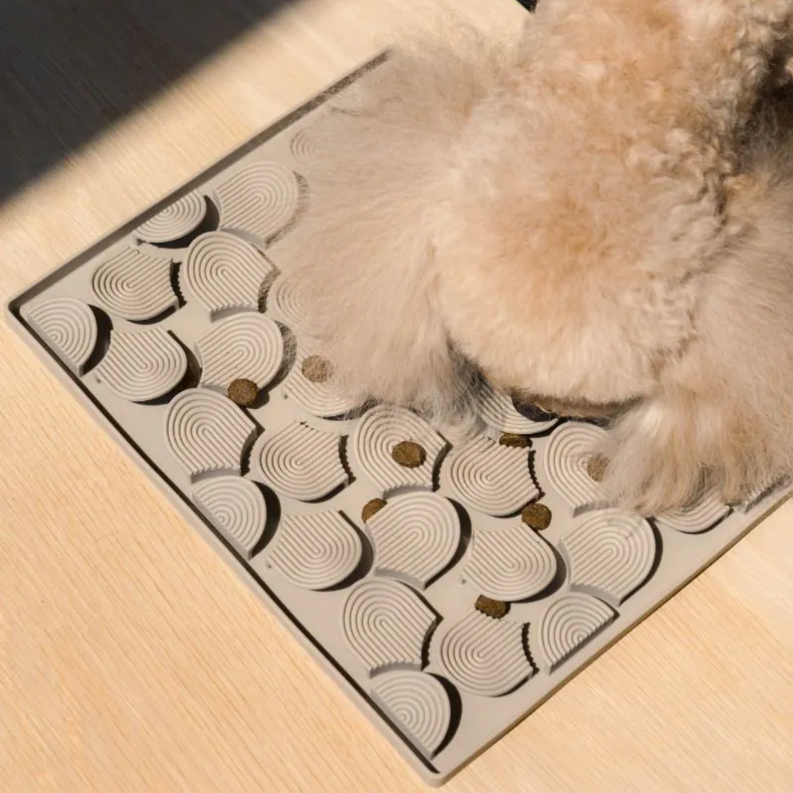 Dog pawing at a patterned mat on a wooden floor