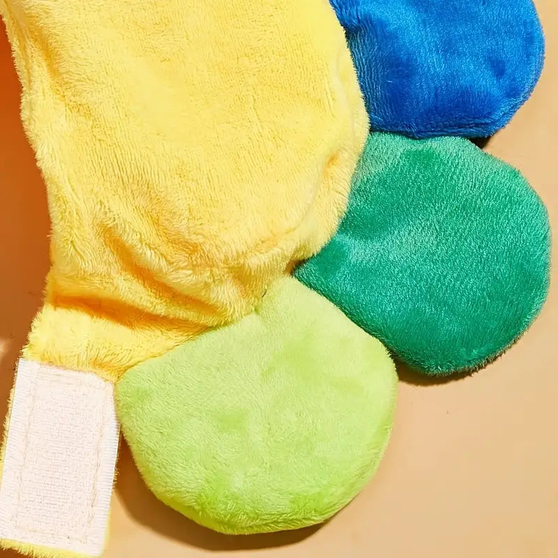 Close-up of a colorful plush toy with yellow, blue, green, and white sections on a beige background.