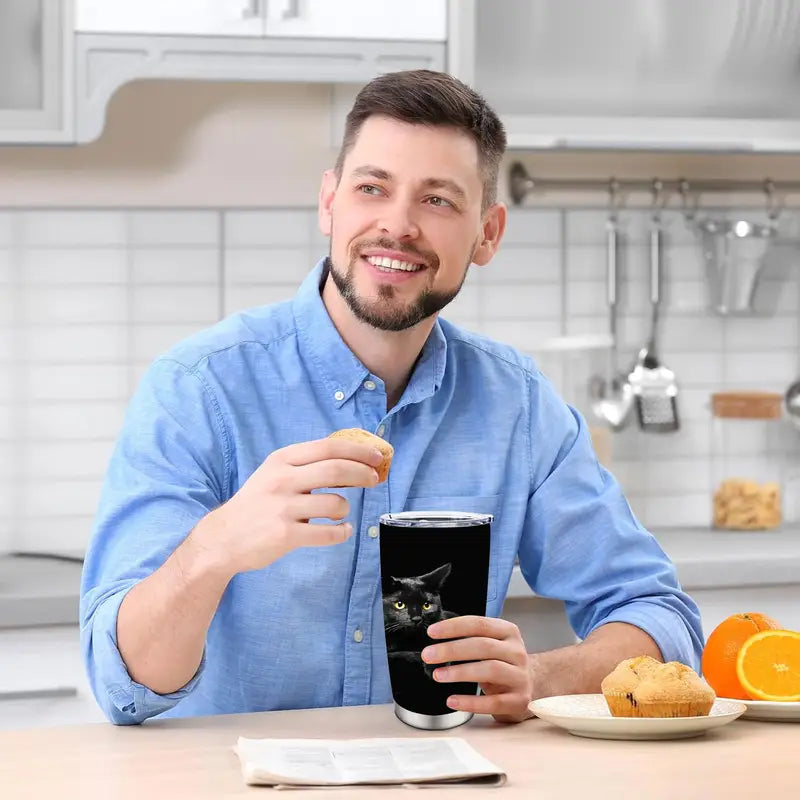 Man in a kitchen holding a mug with a cat design, surrounded by breakfast items.