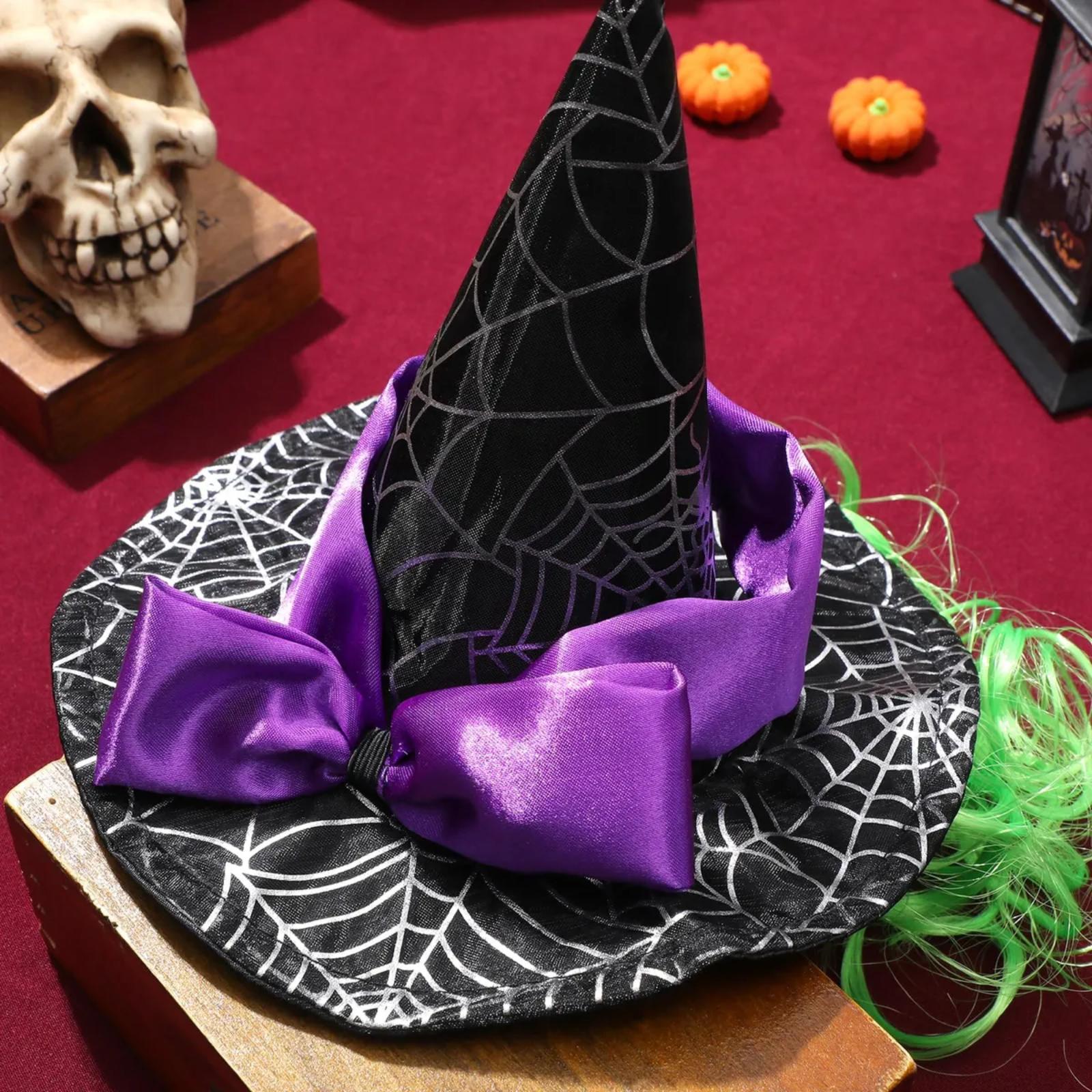 Halloween-themed witch hat with purple ribbon on a spider web-patterned base.