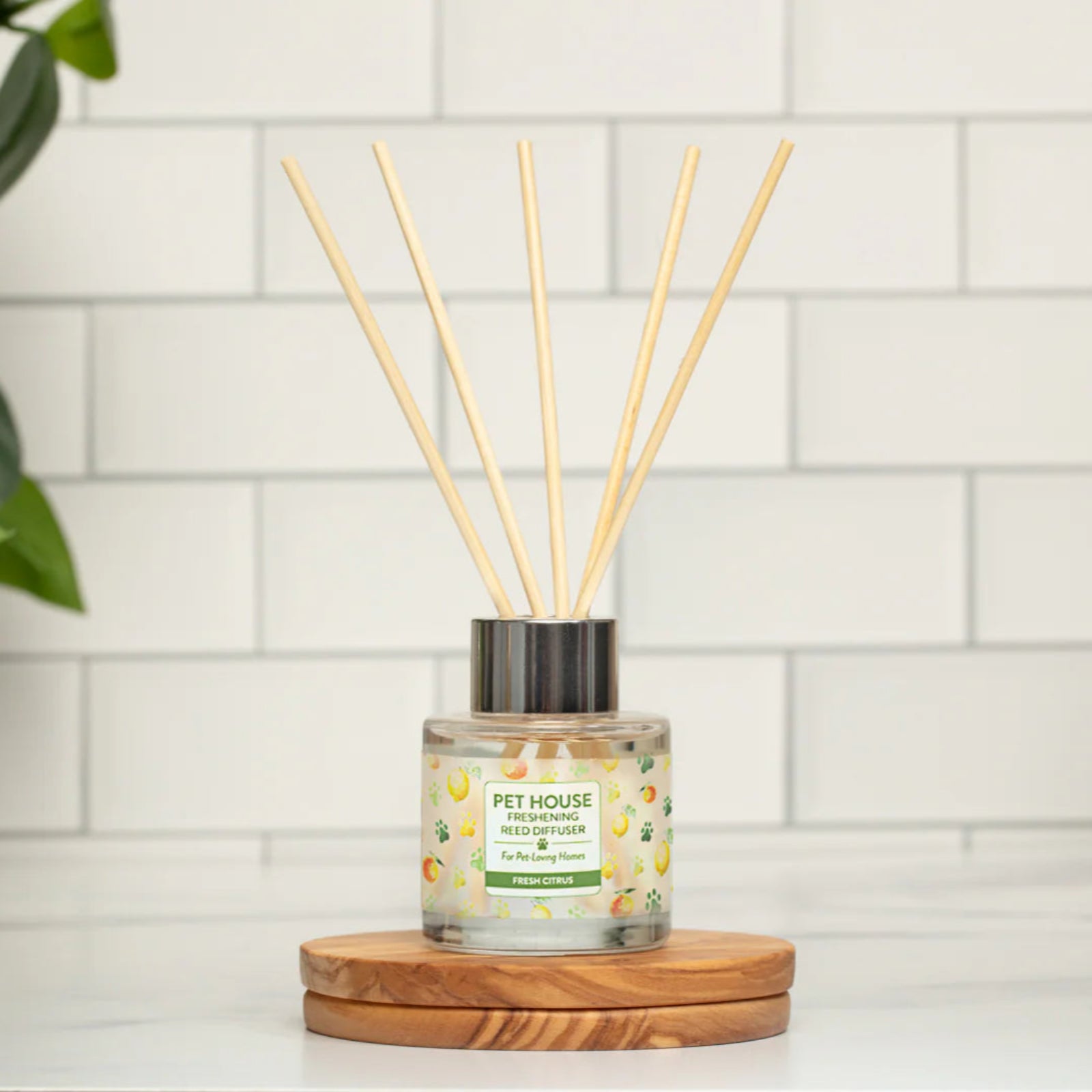 Diffuser with sticks on a wooden coaster against a tiled wall background