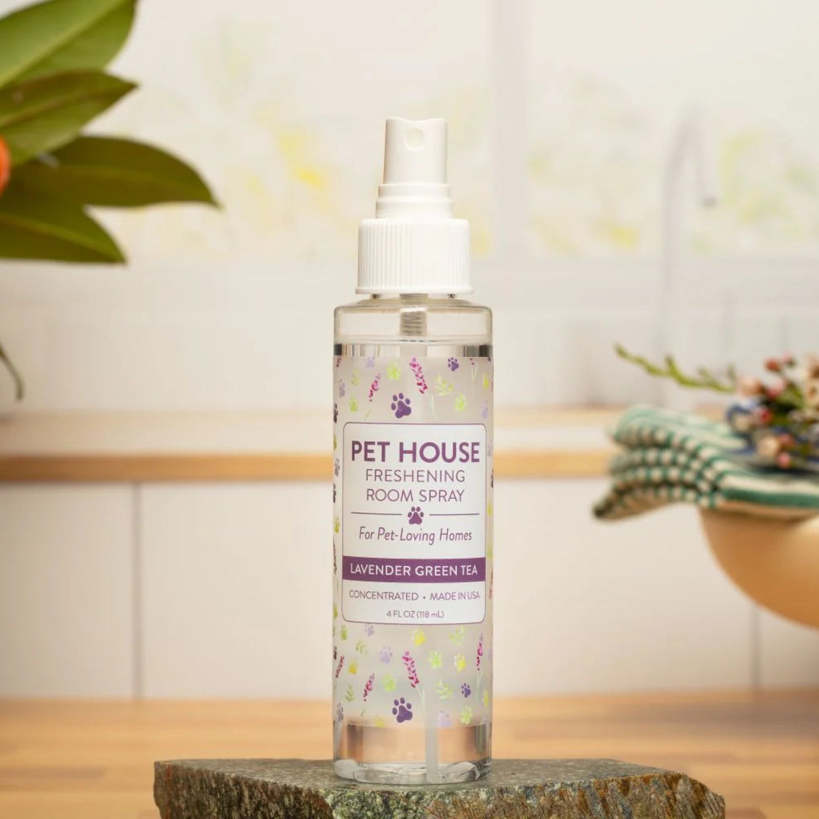Pet House room spray bottle on a wooden surface with decorative elements in the background