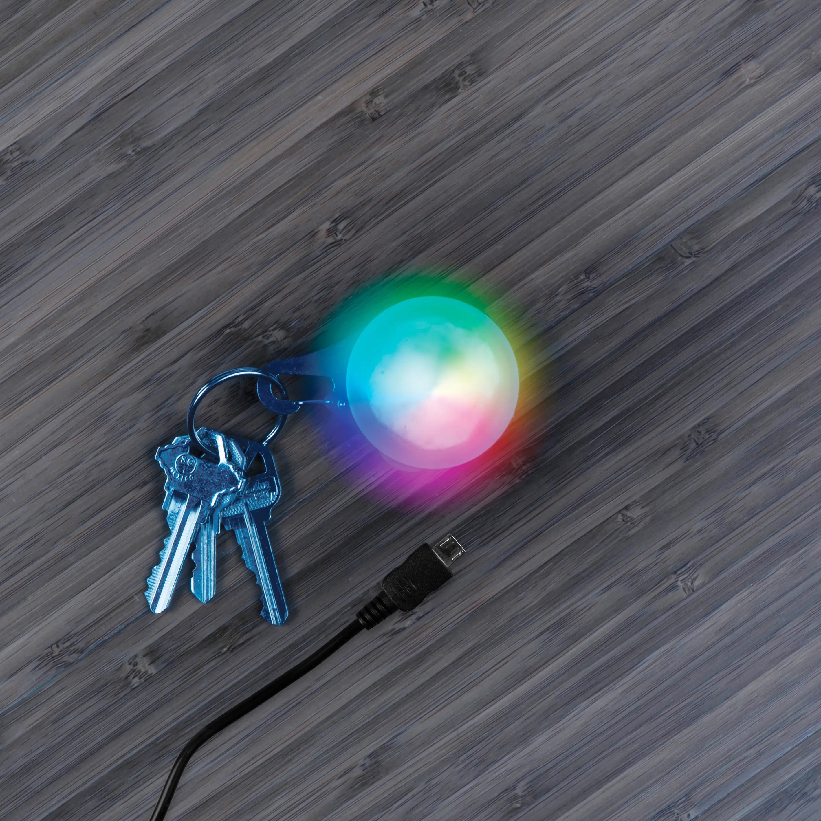 Colorful LED light attached to keys on a wooden surface