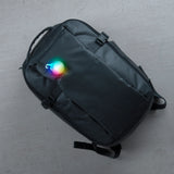 Black backpack with a colorful light on a gray surface