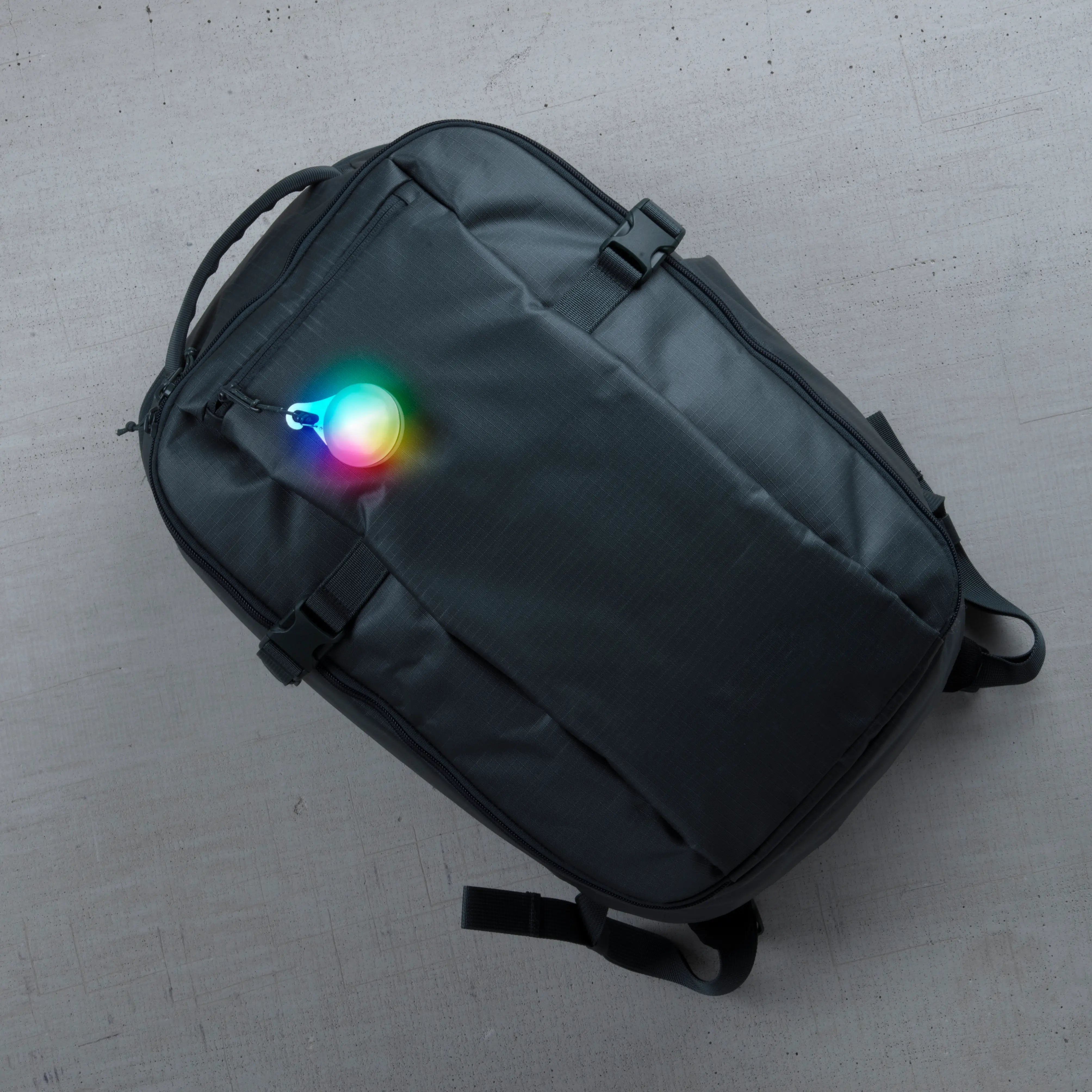 Black backpack with a colorful light on a gray surface