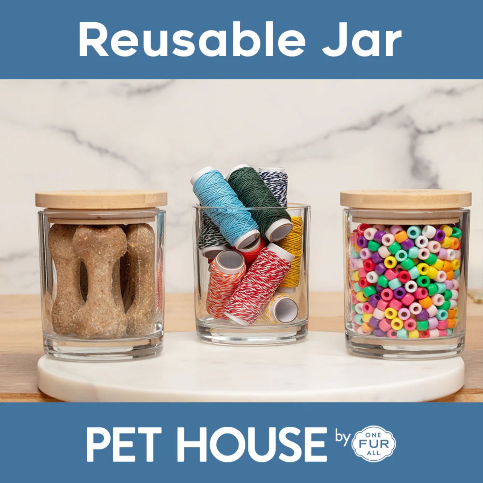 Three glass jars with wooden lids containing dog treats, thread spools, and colorful beads on a marble surface. 'PET HOUSE by FUR' branding is visible.