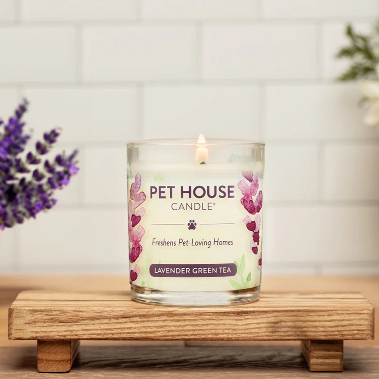 Pet House Candle on a wooden stand with flowers in the background