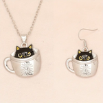 Cat in a teacup necklace and earrings on a beige background