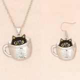 Cat in a teacup necklace and earrings on a beige background