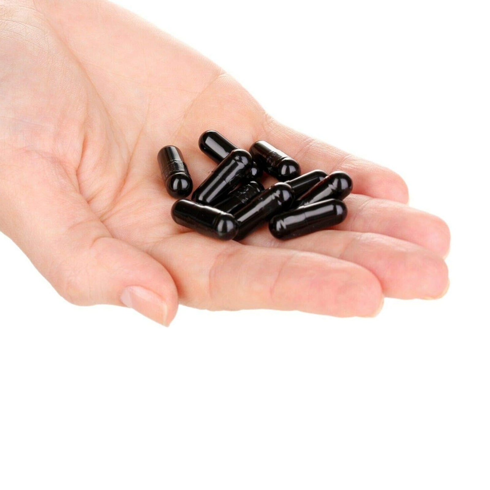 Hand holding black胶囊s on a white background