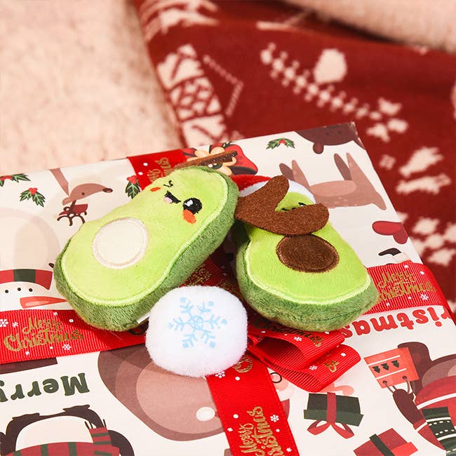 Avocado-shaped toy with a reindeer face on a Christmas-themed gift bag.