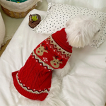 Red knitted dog sweater with reindeer pattern on a white surface