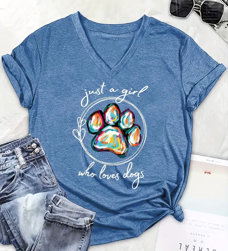 Blue t-shirt with colorful paw print and text 'just a girl who loves dogs' on a white surface with jeans and sunglasses.