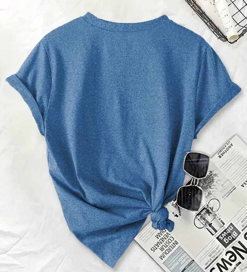 Blue t-shirt with a knot on a white surface with sunglasses and a newspaper.