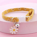 Yellow floral-patterned pet collar with a white flower charm and bell on a pink background