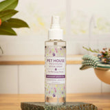 Pet House room spray bottle on a wooden surface with decorative elements in the background