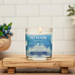 Pet House Candle on a wooden stand with a white tiled wall and decorative elements in the background