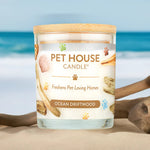 Pet House Candle labeled 'Ocean Driftwood' on a beach with ocean in the background
