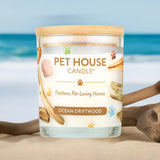 Pet House Candle labeled 'Ocean Driftwood' on a beach with ocean in the background